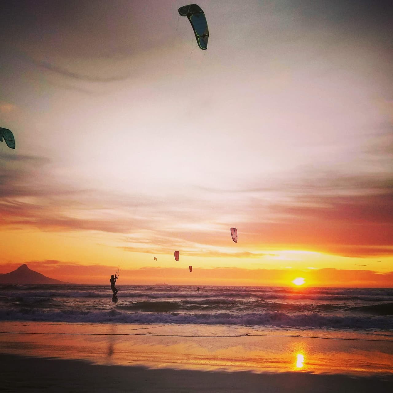 A kitesurfer on the water at sunset off Bloubergstrand