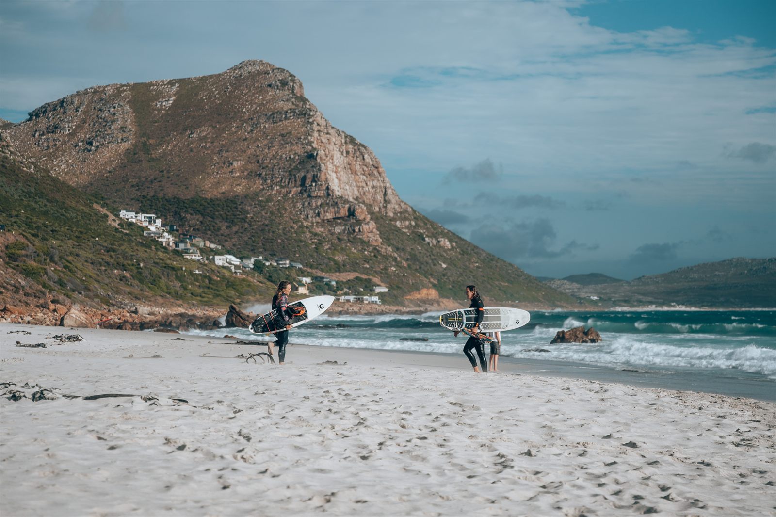A kitesurfer carving a wave on a directional board off Bloubergstrand